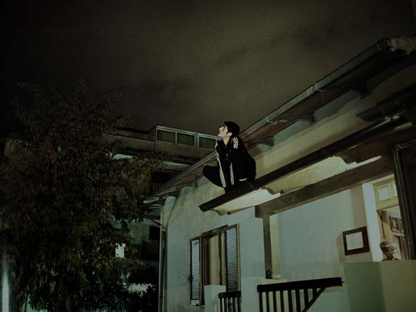 © Alvaro Deprit. Alem, un ragazzo della casa famiglia, sopra il tetto della casa. Da Suspension